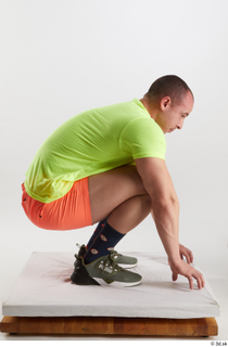 Joel  1 dressed green sneakers kneeling orange shorts sports…